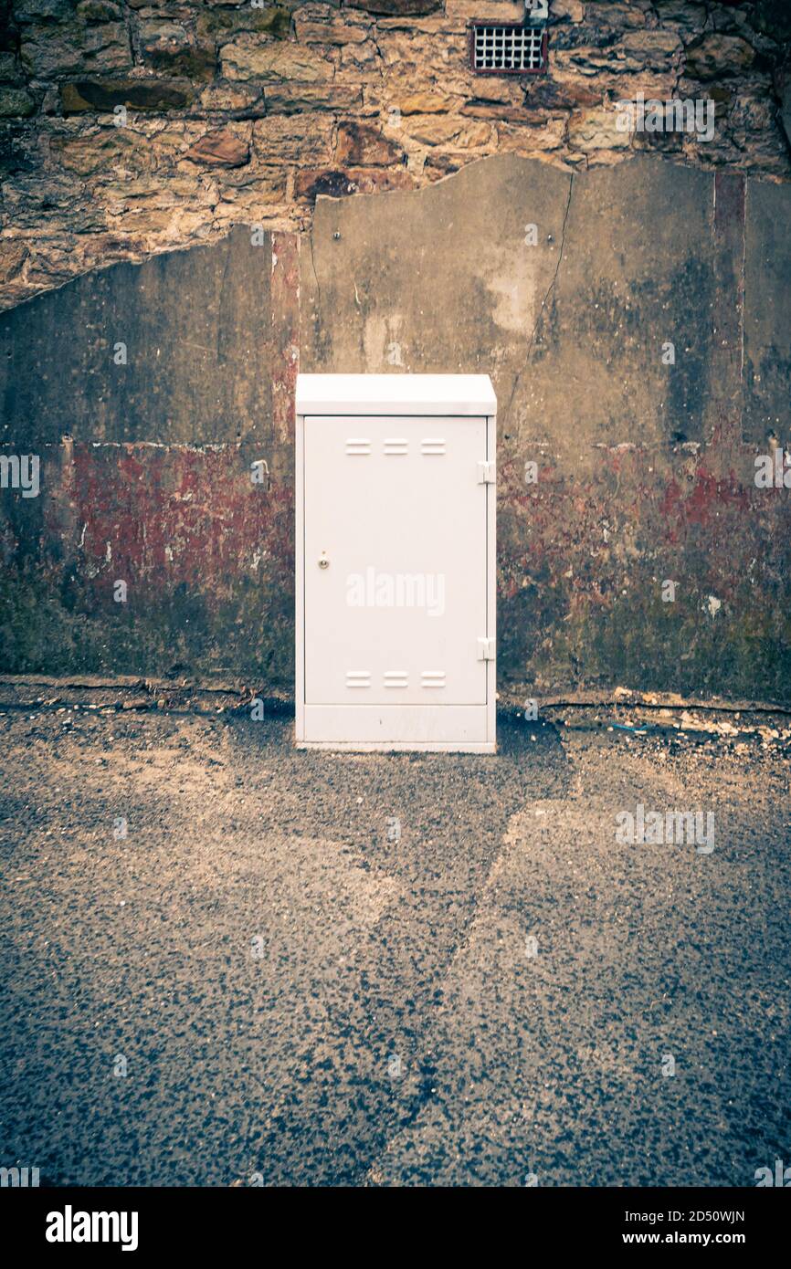Una nuova scatola di derivazione per servizi via cavo su un percorso vicino a un vecchio muro di pietra a Consett, County Durham, Regno Unito Foto Stock