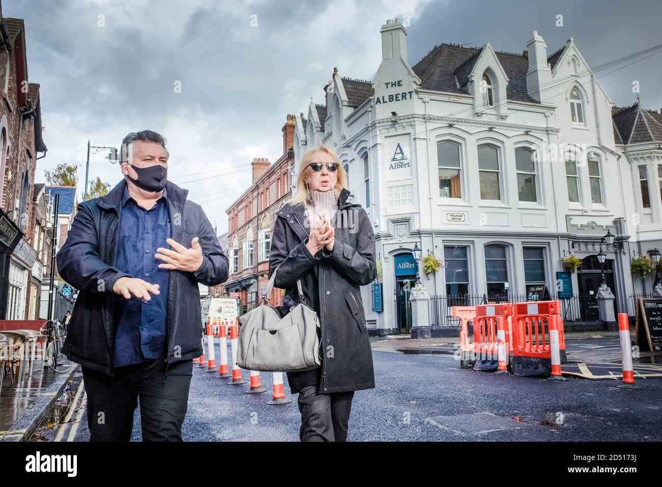 Liverpool Covid-19 Coronavirus blocco. Uomo mascherato e donna non mascherata strofinando le mani a Liverpool camminate davanti ad un pub e bar. Foto Stock
