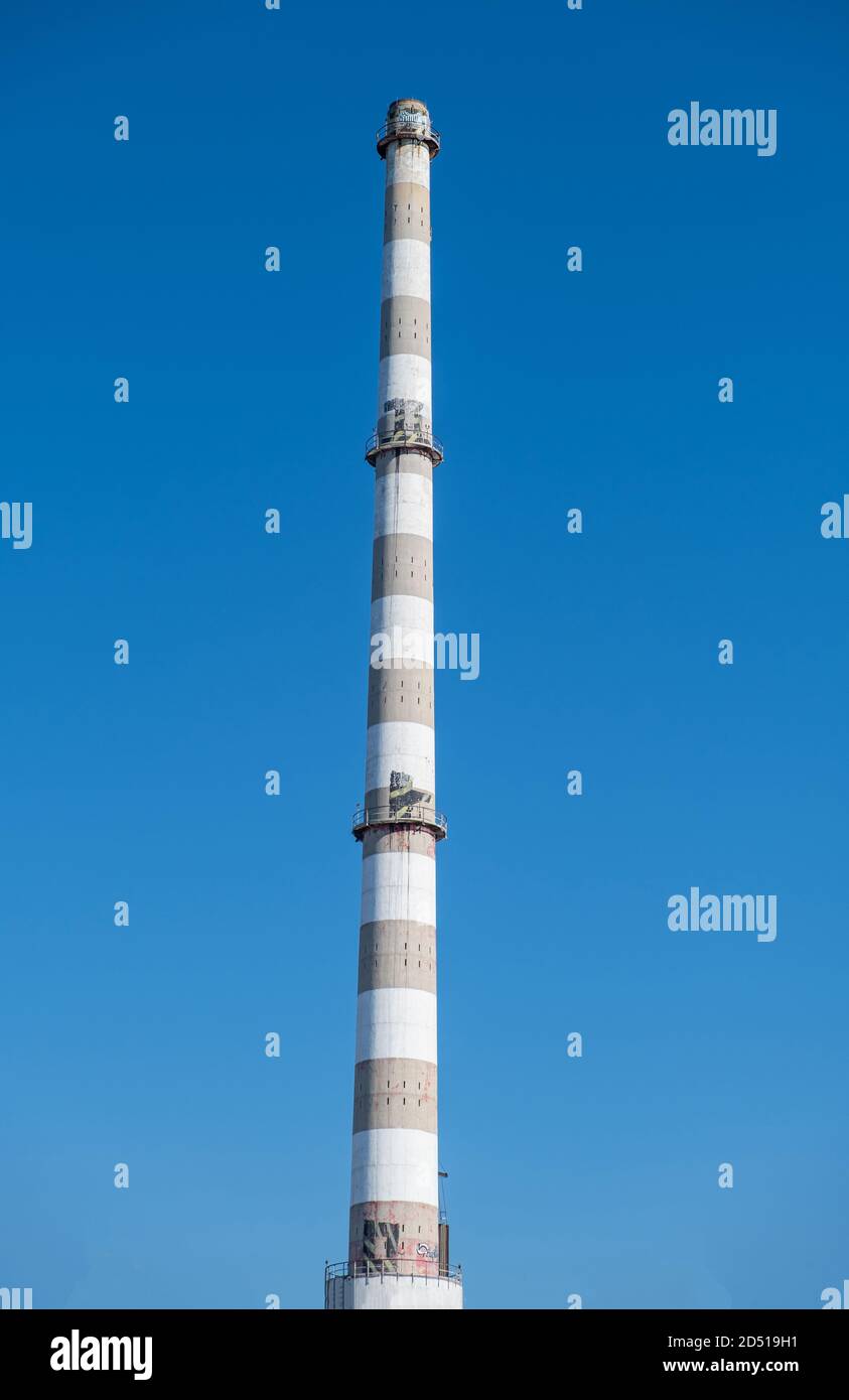 Vecchio camino industriale di imisioni di fabbrica. Alta pila di cemento contro sfondo blu cielo, giorno di sole. Foto Stock