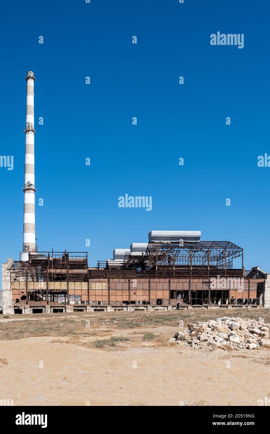 Vecchio stabilimento industriale abbandonato. Costruzione di fabbrica di fertilizzanti e rovine di camino a Drapetsona Pireo Grecia, cielo blu, giorno di sole. Foto Stock