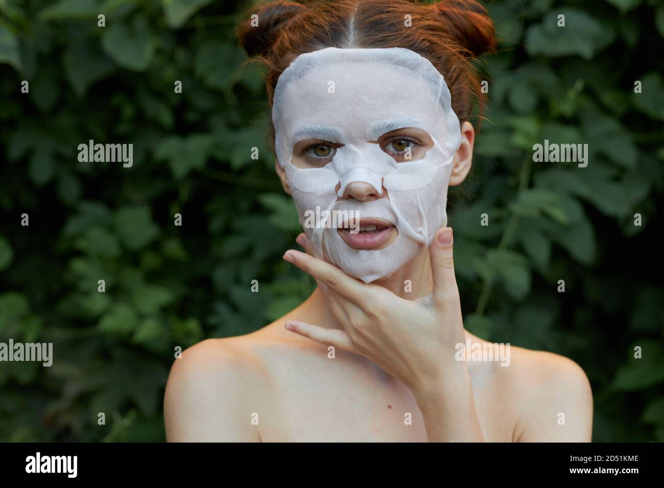 Bella donna maschera anti-rughe in natura, tocca il viso nuda spalle  cespugli sullo sfondo Foto stock - Alamy