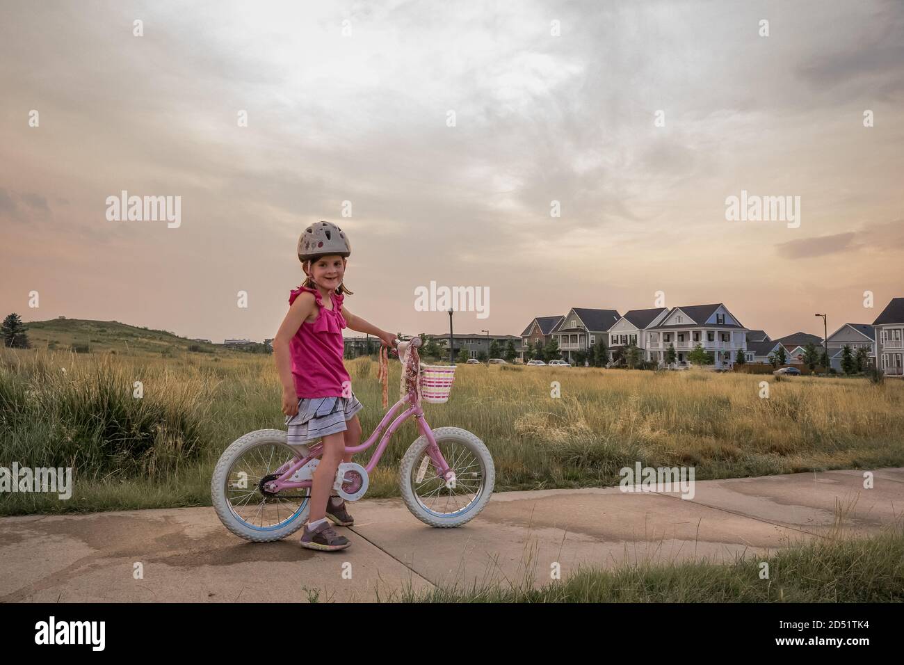 ritratto di giovane ragazza sorridente seduta sulla sua moto dentro un parco al tramonto Foto Stock