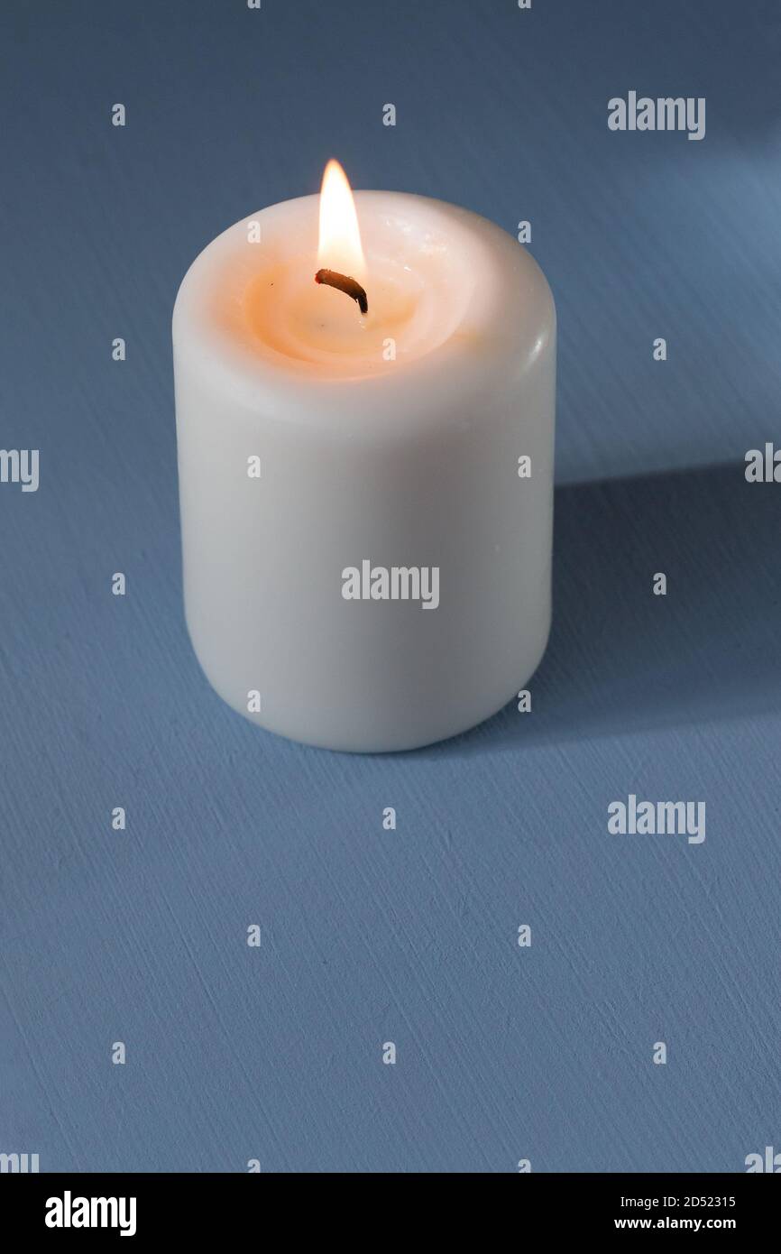 candela bruciante su sfondo azzurro Foto Stock