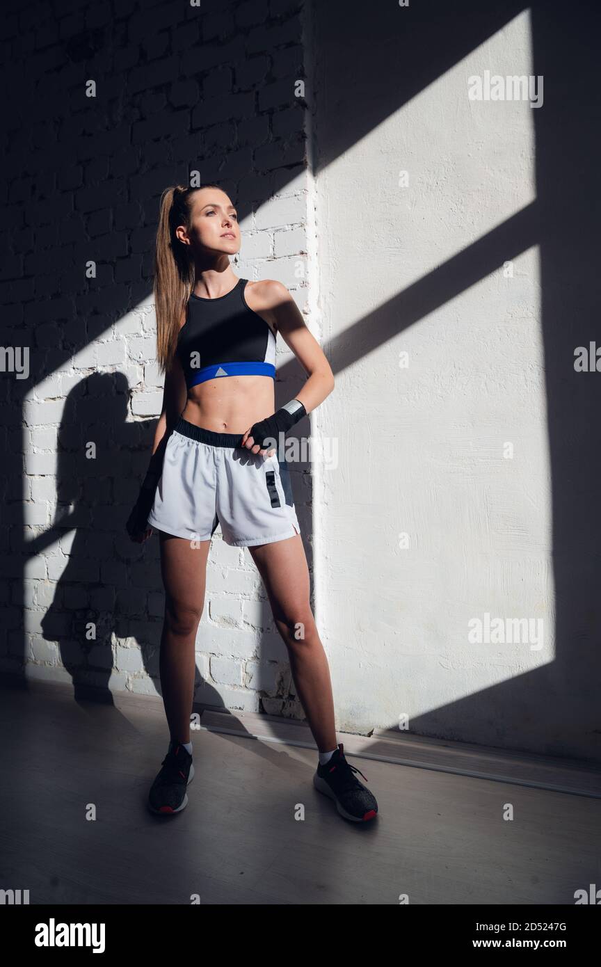 Una bella bruna dai capelli lunghi di costruzione atletica si leva contro un muro di mattoni nel loft Foto Stock