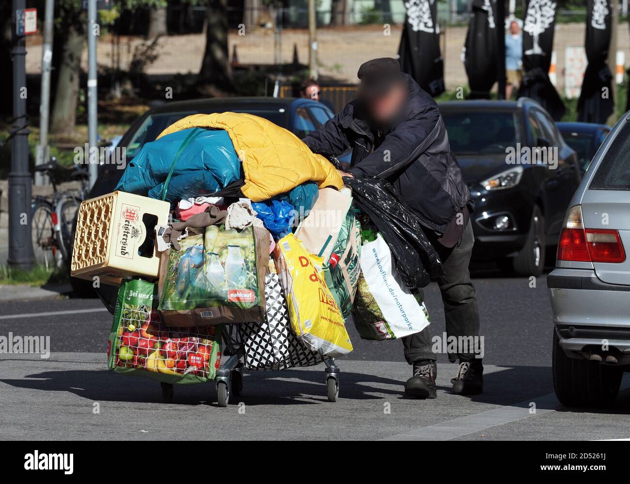 Berlino, Germania. 04 ottobre 2020. Un uomo spinge un carrello con borse di  plastica da Rewe, Netto, Nahkauf e Kaufland, una cassa vuota di birra e  coperte davanti a lui attraverso la