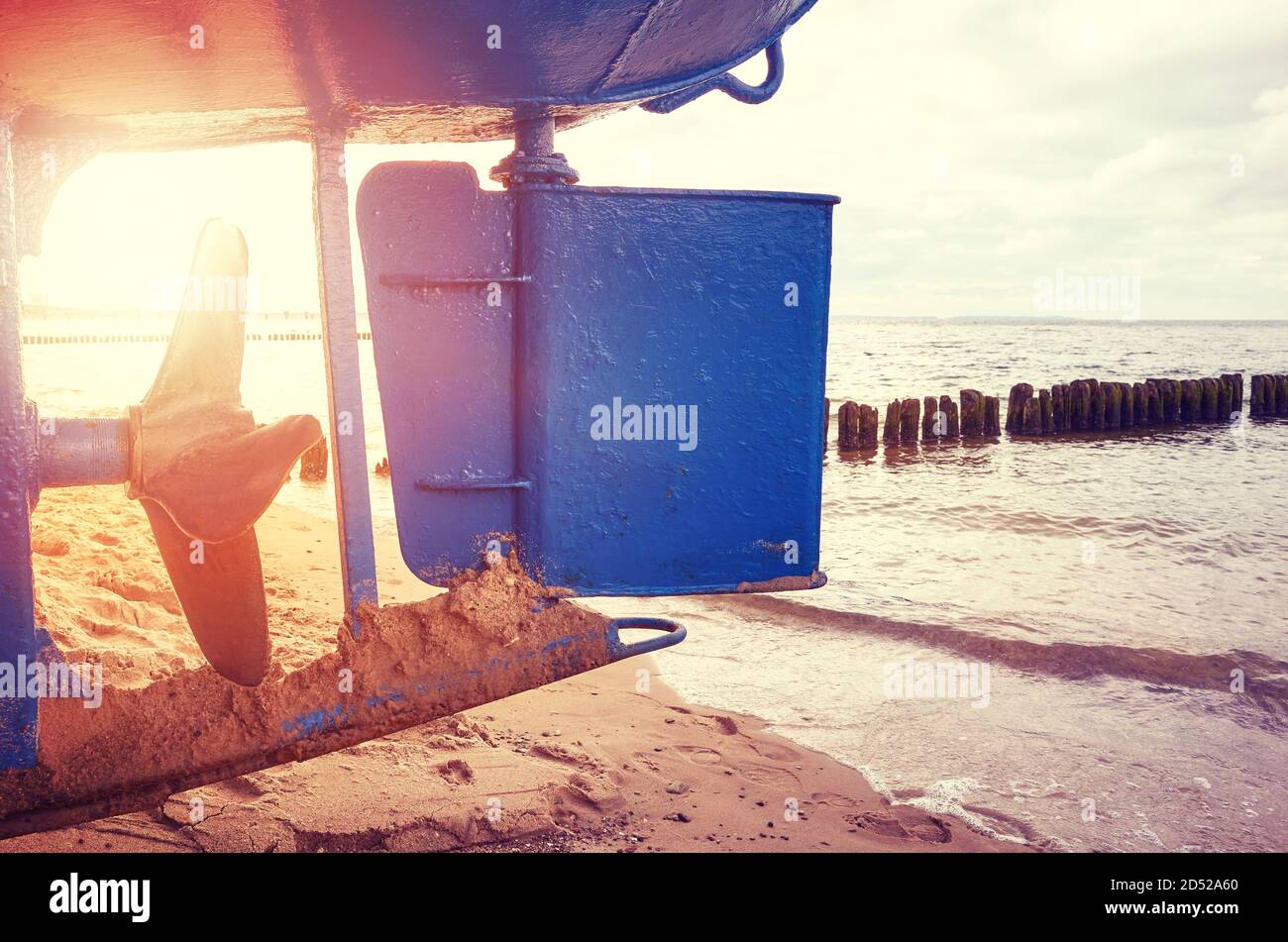 Timone di barche da pesca e elica su una spiaggia al tramonto, colore tonificante applicato. Foto Stock