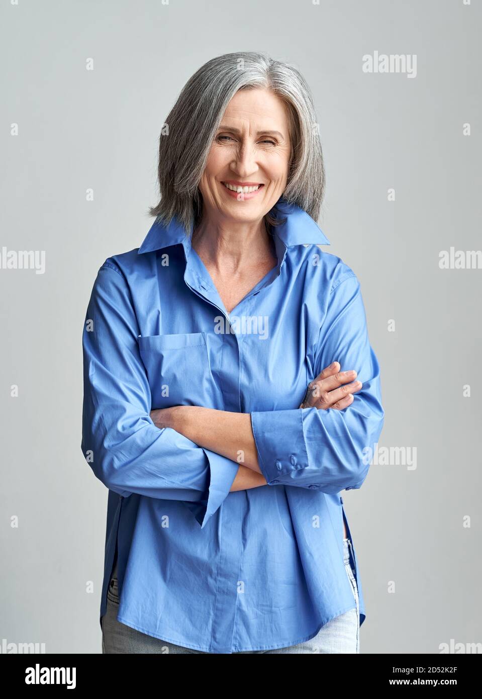 Sorridente elegante donna dai capelli grigi maturi con le braccia incrociate, ritratto. Foto Stock