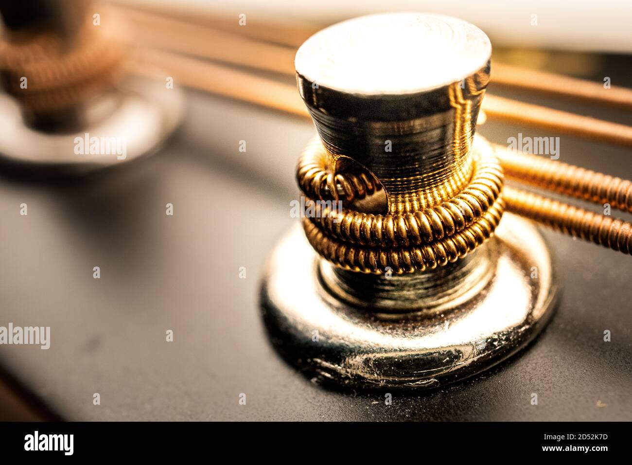 Macro foto di intonacatura di mandolino in argento con filo avvolto intorno e stringhe in background Foto Stock