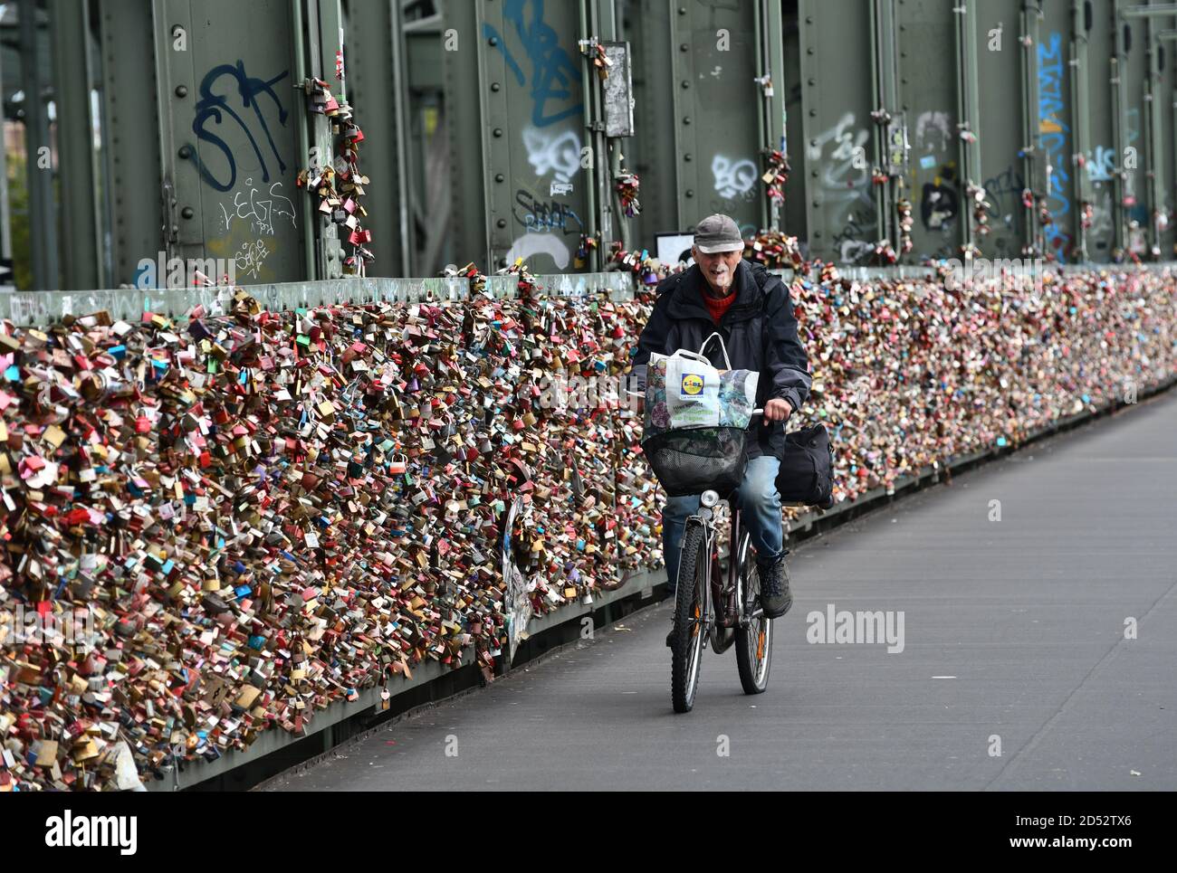 Colonia, Germania, 2020. L'uomo in bicicletta ha passato migliaia di chiuse d'amore sul ponte Hohenzollern che attraversa il fiume Reno Hohenzollernbrücke Foto Stock