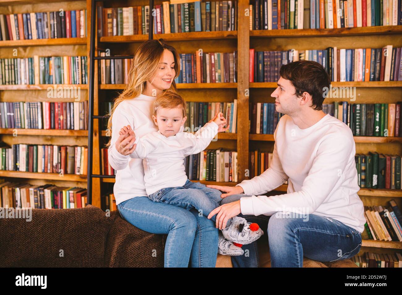 Bella famiglia con bambino vestito con gli stessi vestiti si divertono sul  divano a casa durante il Natale. Concetto di Natale per la famiglia. Felici  i genitori con cute Foto stock -