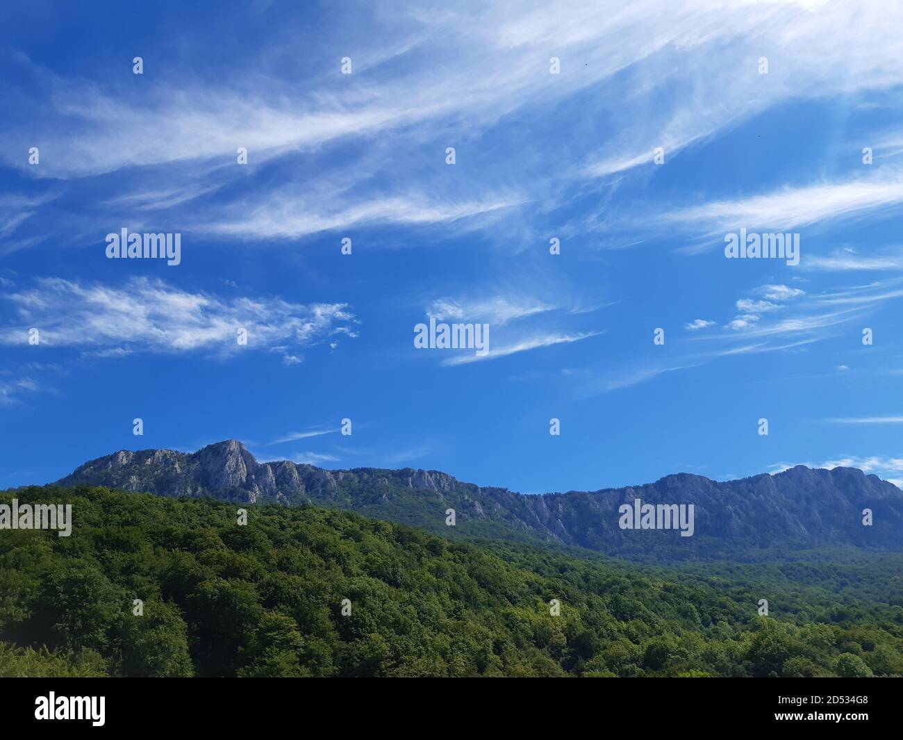 Panoramica di un paesaggio montano con sottili nuvole di fondo Foto Stock