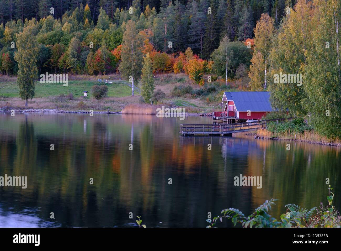 Boathouse rosso con foresta in colori autunnali sullo sfondo Foto Stock