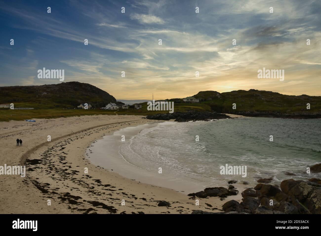 Achmelvich Beach, North Coast 500, Scotland, UK con una coppia solitaria che cammina sulla sabbia al tramonto Foto Stock