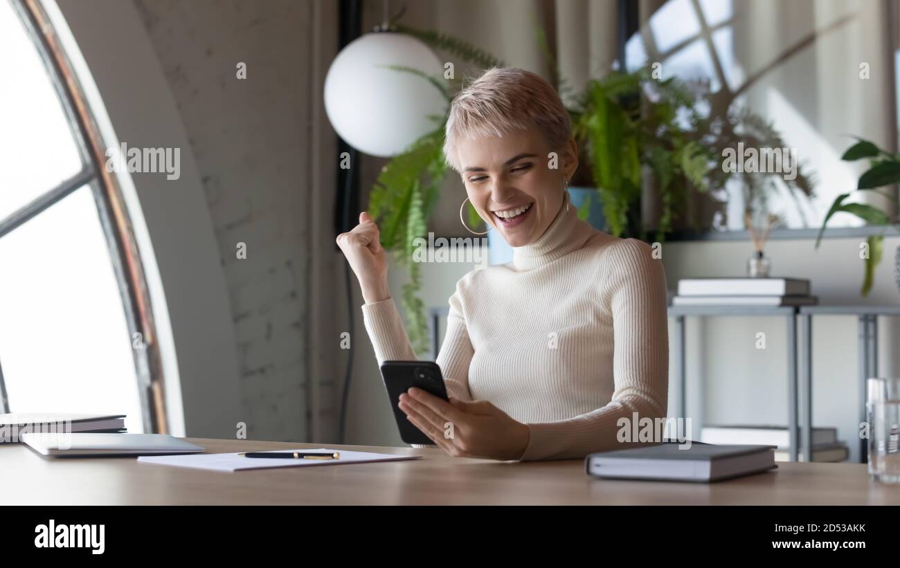 Una donna entusiasta riceve un messaggio piacevole sul cellulare Foto Stock