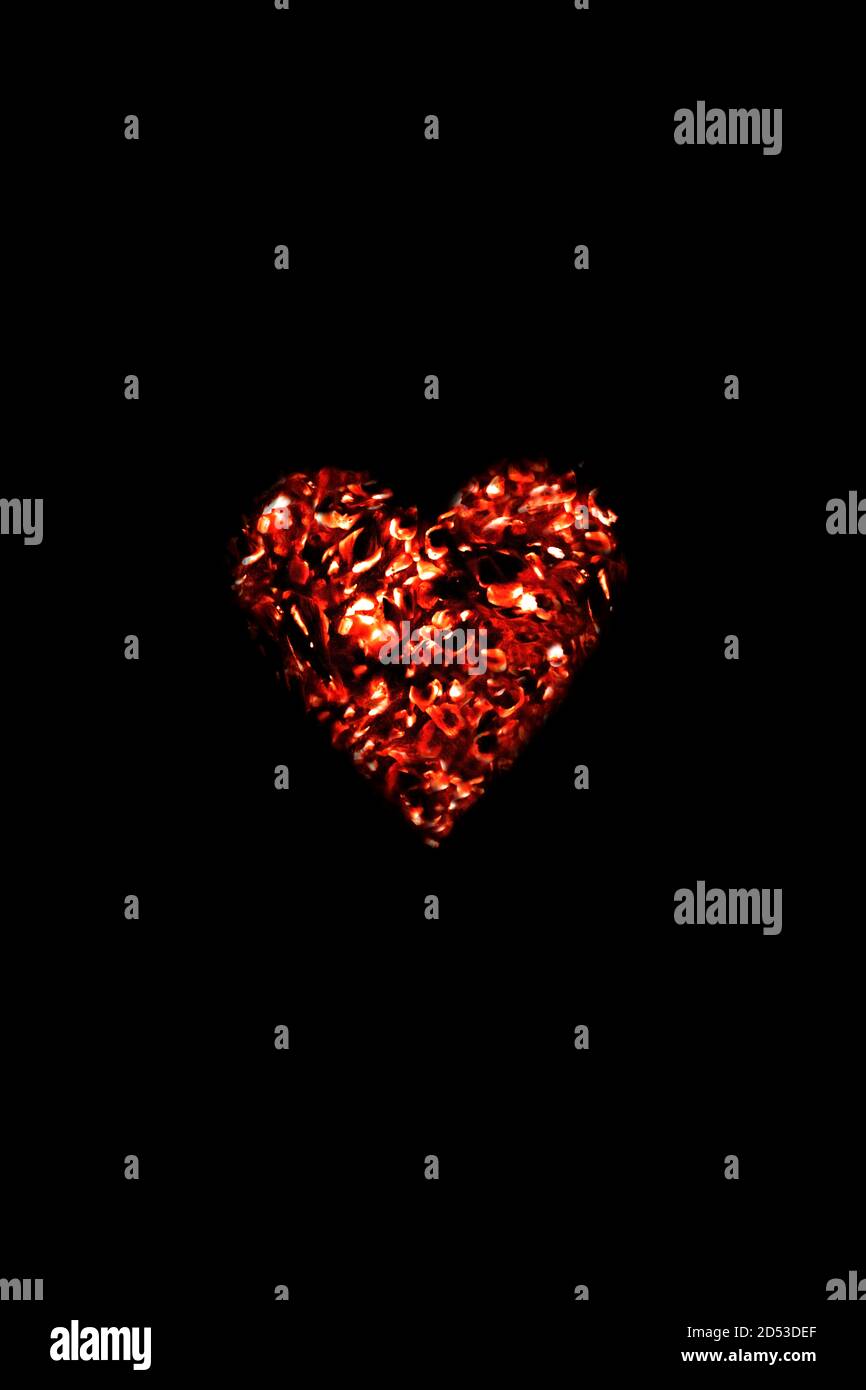 Vista romantica e scura della brace ardente a forma di cuore. Foto Stock