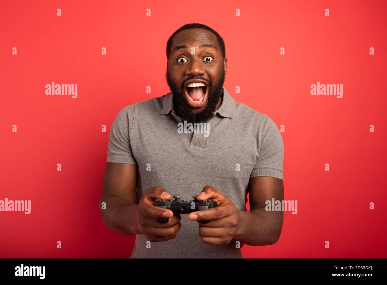 Happy man gioca con un videogioco su sfondo rosso Foto Stock