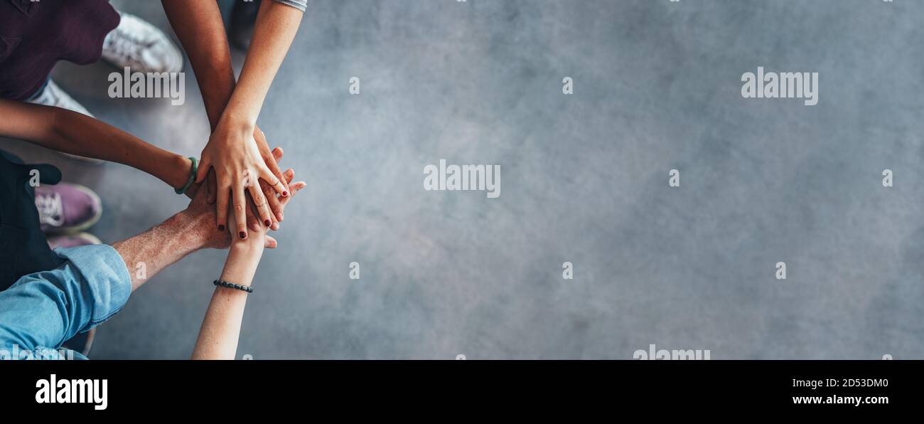 Le mani della gente sopra l'una dell'altra. Vista dall'alto del gruppo giovane con le mani sullo stack che simboleggia il lavoro di squadra. Foto Stock