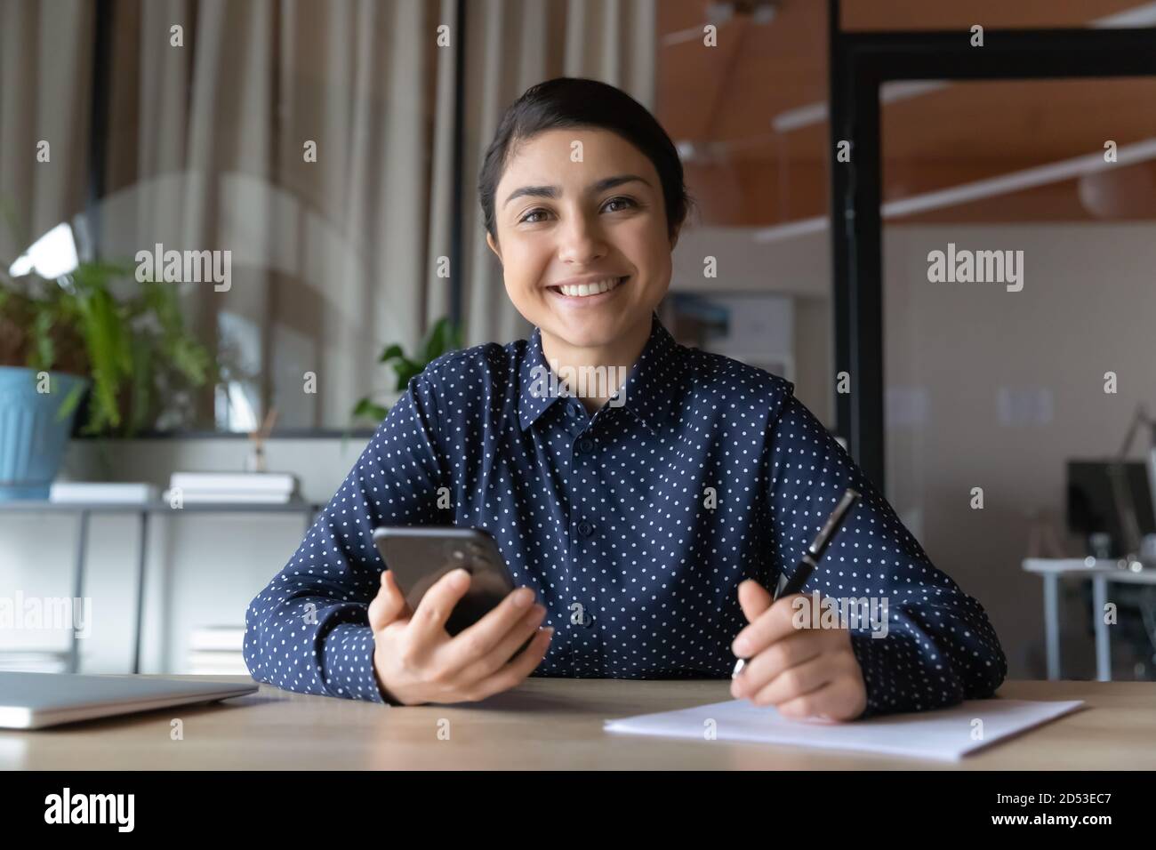 Ritratto di sorridente studio di donna indiana utilizzando il cellulare Foto Stock