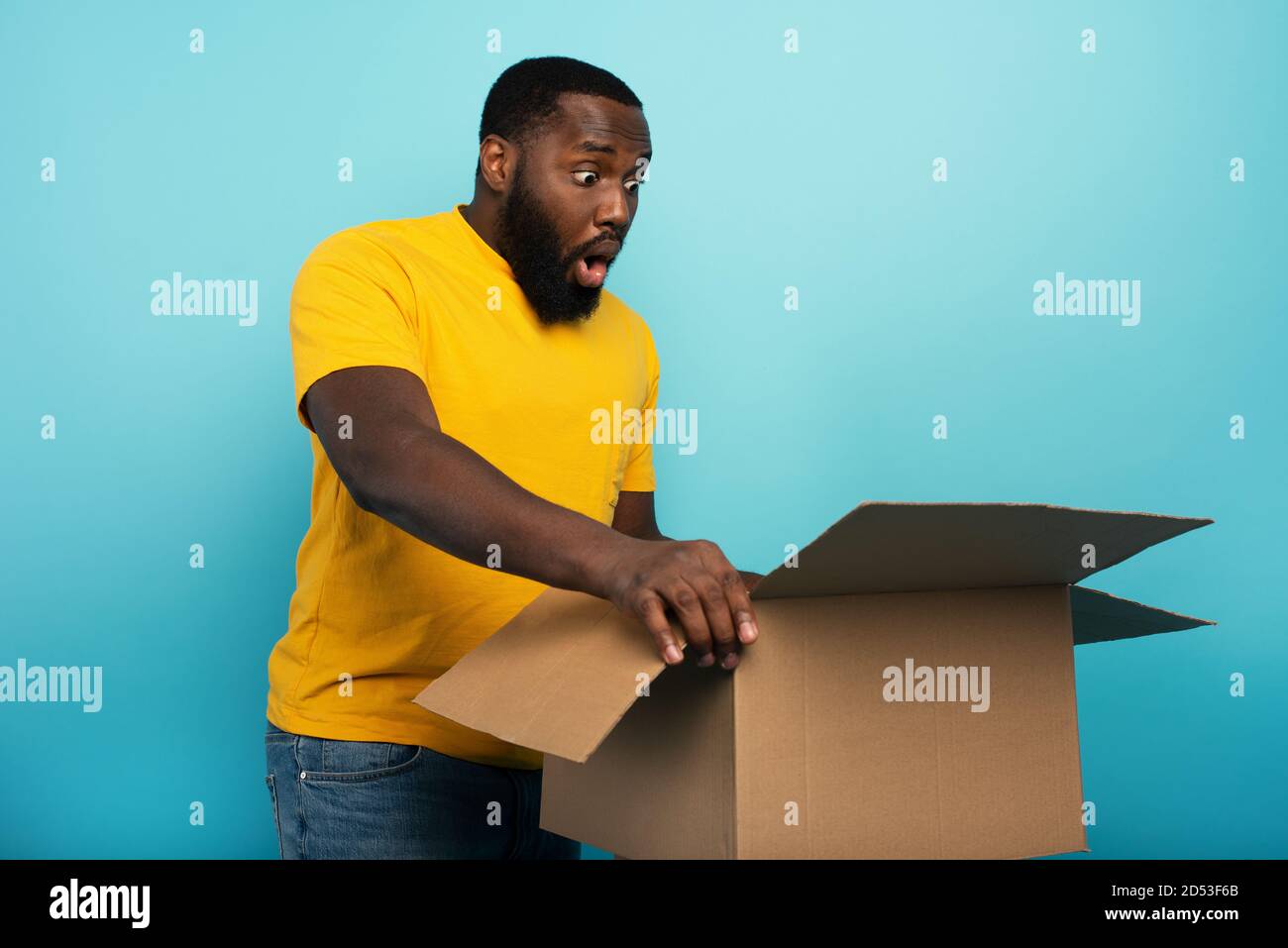 Happy Boy riceve un pacchetto dall'ordine del negozio online. Espressione felice e sorpresa. Sfondo blu. Foto Stock