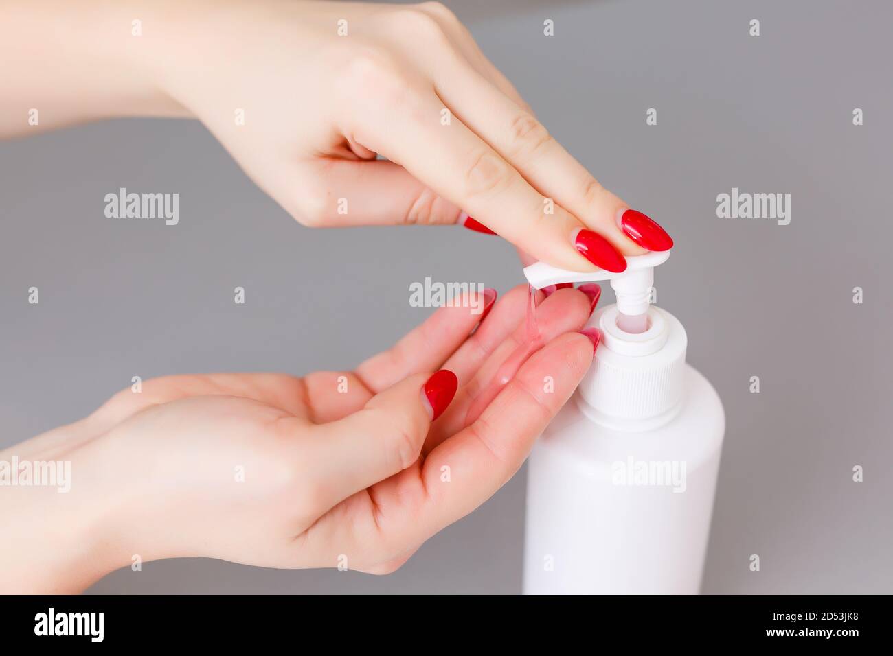 Donna premere sul dispenser e strizzare il gel di sapone morbido sul palmo, colpo di closeup su fondo piatto. Sapone liquido trasparente utilizzato per il lavaggio delle mani Foto Stock