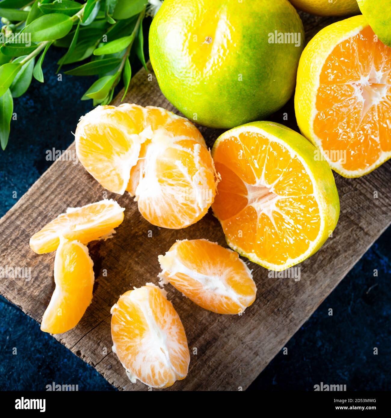 Frutta Mandarina matura sbucciata aperta e posto su vecchio legno rustico aspetto con gruppo di frutta e foglie di mandarino. Frutta invernale. Foto Stock