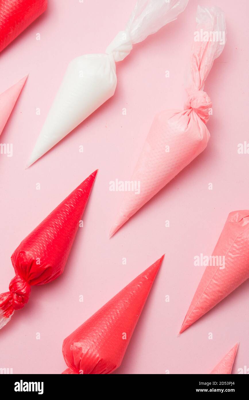 I sacchetti di tubazione con i colori variano dal bianco al rosso, con gradazione differente sopra uno sfondo rosa Foto Stock