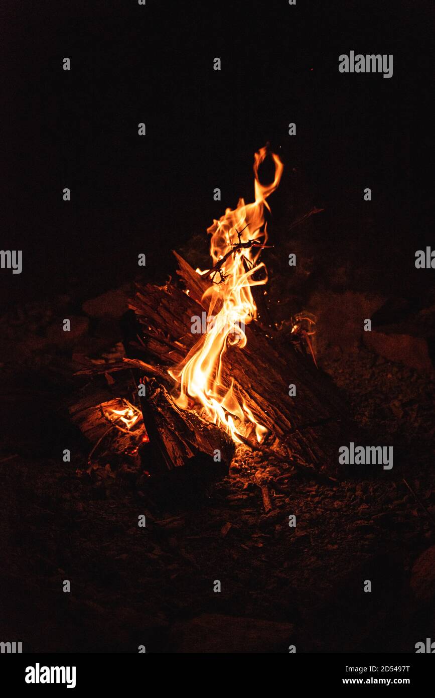 Primo piano delle fiamme di un falò che si arriccia intorno a legna in fiamme. Foto Stock