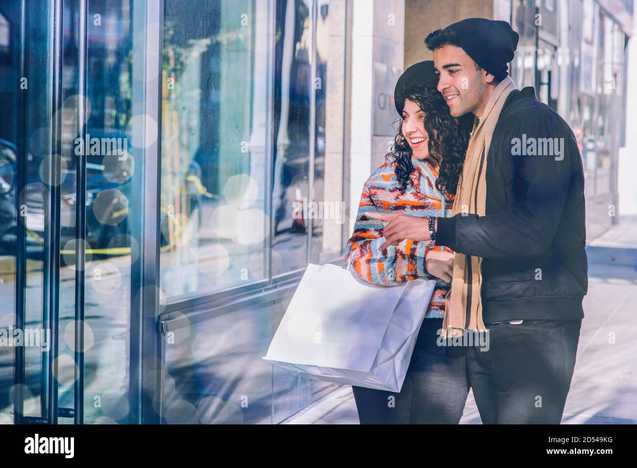 Millenario sorriso maschile e femminile durante lo shopping durante le vacanze - stagione invernale - freddo - luci Foto Stock