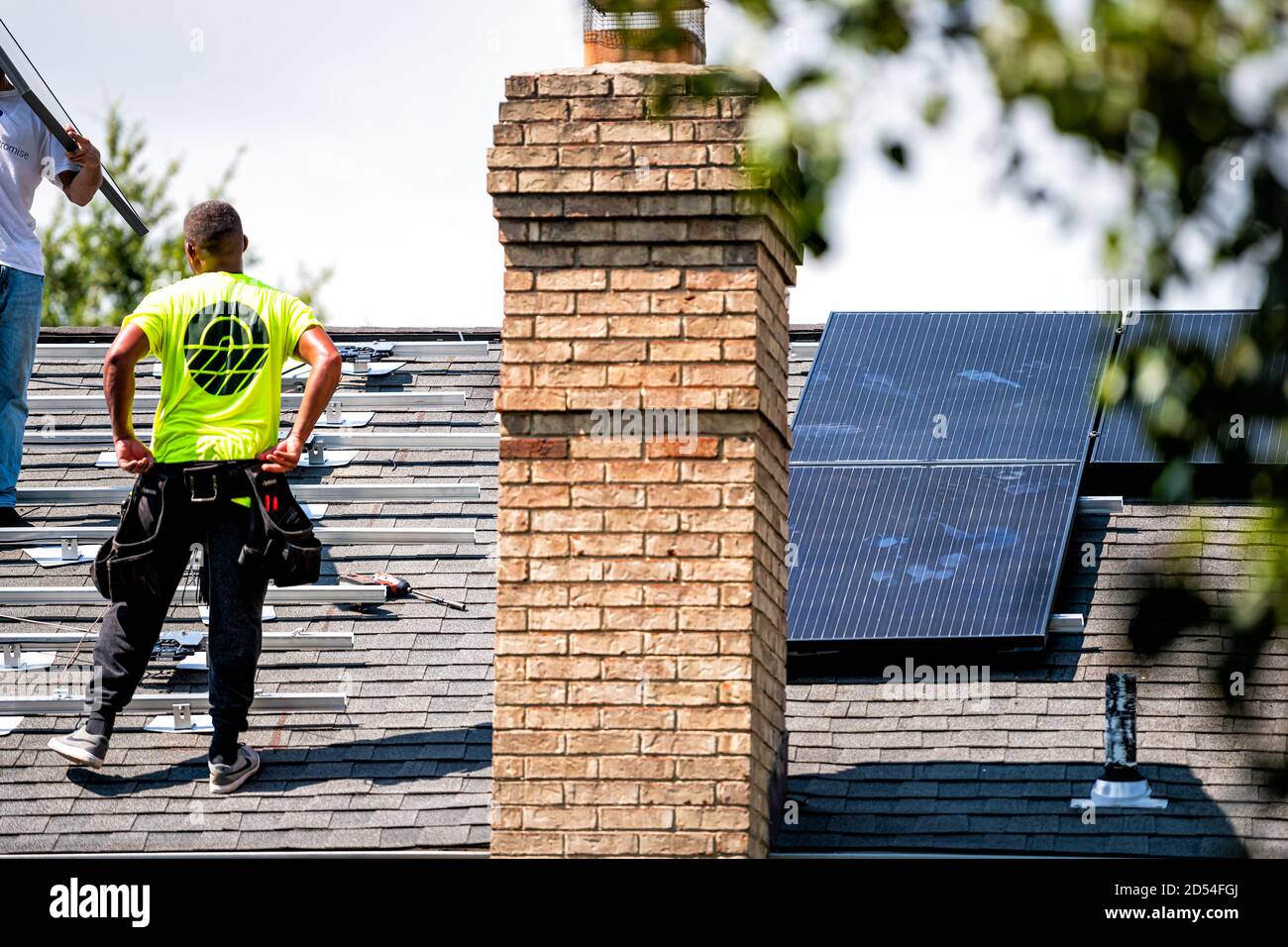 Herndon, Stati Uniti d'America - 27 agosto 2020: Operaio di uomo che installa lavorando sui pannelli solari del tetto montati su scaffalature e rotaie sulla parte superiore della casa residenziale h Foto Stock