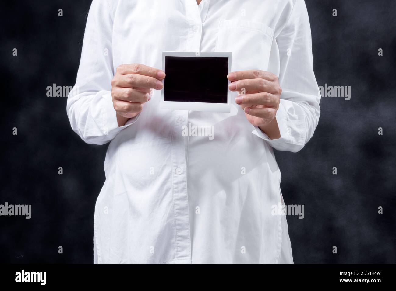 Donna incinta che tiene ecograficamente il risultato del test di gravidanza con fondo nero Foto Stock