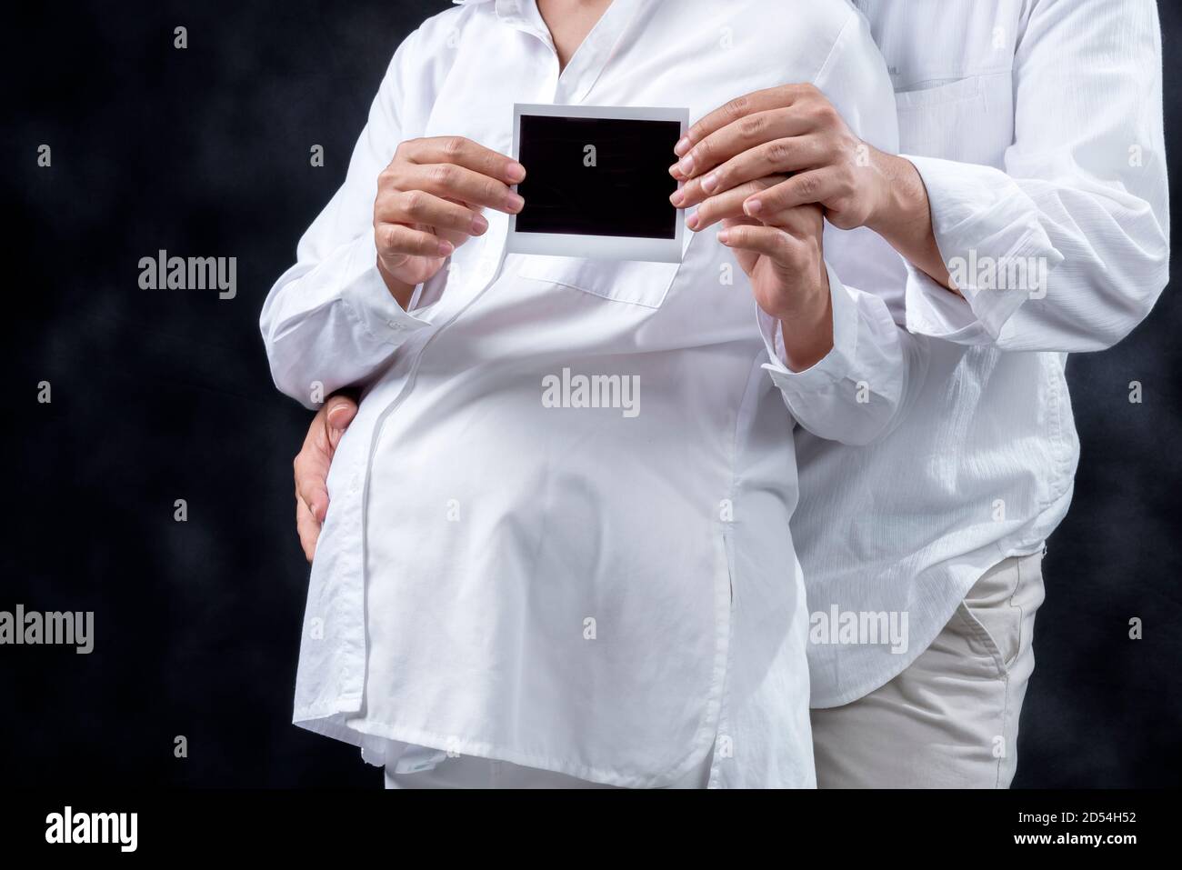 Risultato del test di gravidanza ecografico con sfondo nero per una coppia incinta Foto Stock