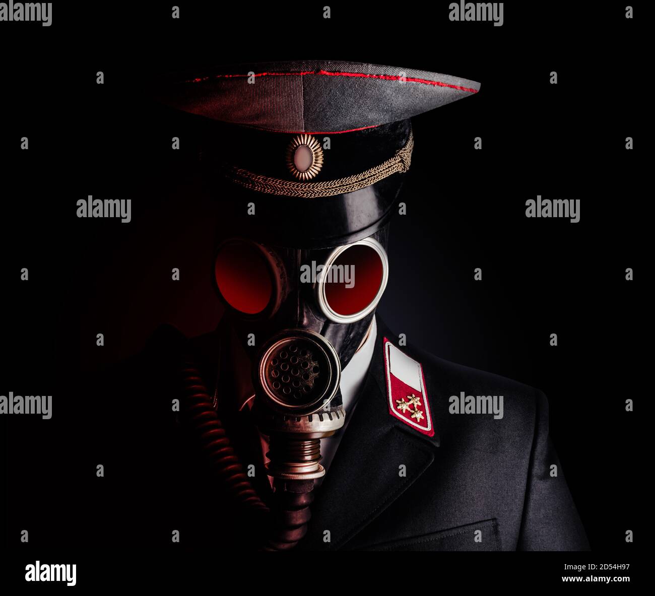 Foto ritratto di un ufficiale militare post apocalittico in tuta uniforme e berretto a picco in piedi nella maschera a gas sovietica su sfondo nero. Foto Stock