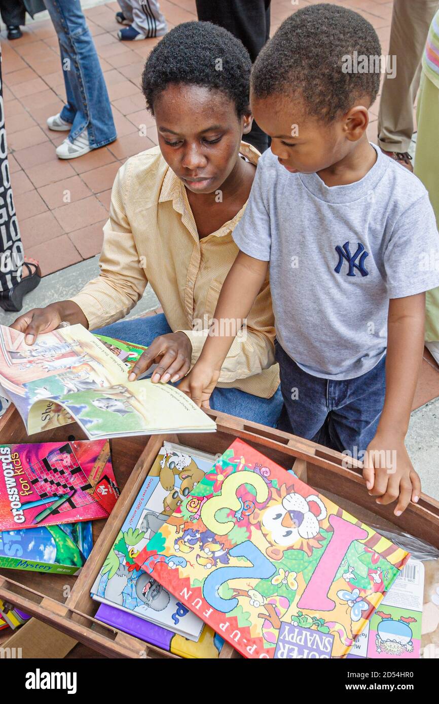 Miami Florida,Dade College Campus,International Book Fair vendor stall seller books,Black African boy son woman female mother look looking children's. Foto Stock