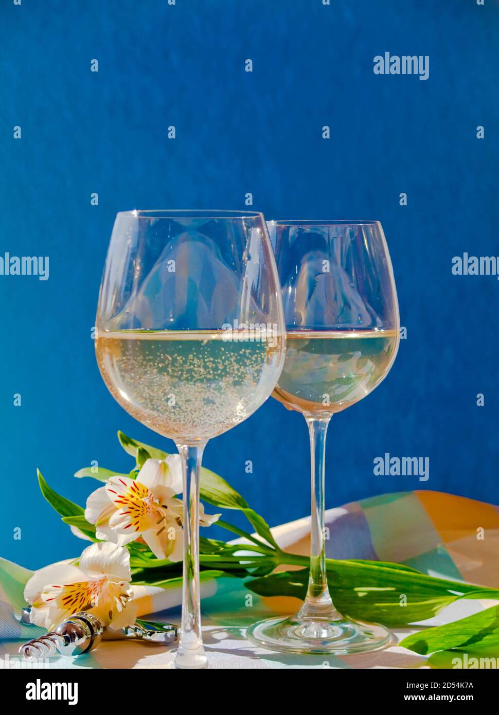 Bicchieri da vino con vino bianco con fiori e blu sfondo con spazio di copia Foto Stock