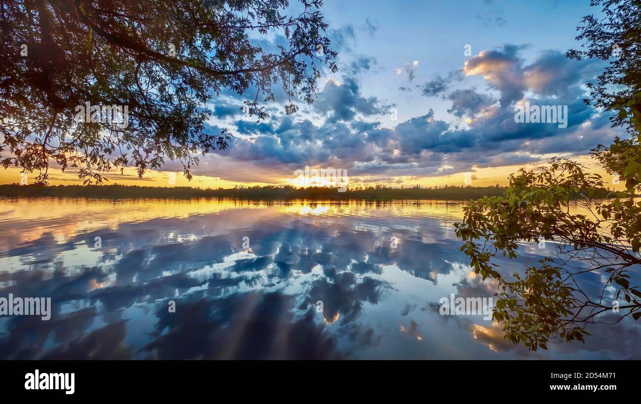 Un bellissimo e suggestivo tramonto estivo con nuvole e raggi solari riflessi su un piccolo lago in Ontario, Canada. Foto Stock