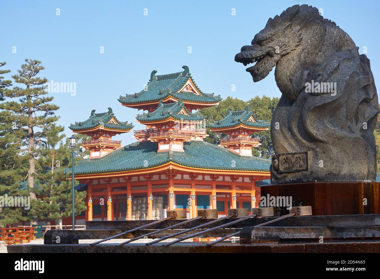 Statua del drago sopra il bacino di abluizione dell'acqua per la purificazione cerimoniale (tsukubai) con vermiglio Byakko-ro Torre del Santuario Heian-jingu sullo sfondo. Foto Stock