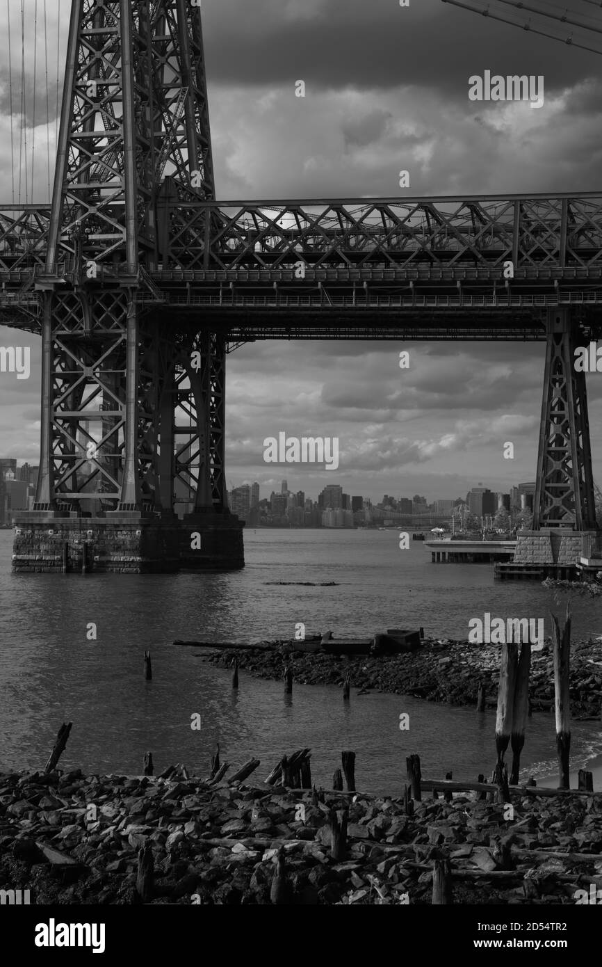 Vista di Manhattan attraverso l'East River sotto il Williamsburg Bridge che collega Brooklyn a Manhattan. Monotono, foto in bianco e nero. New York Foto Stock