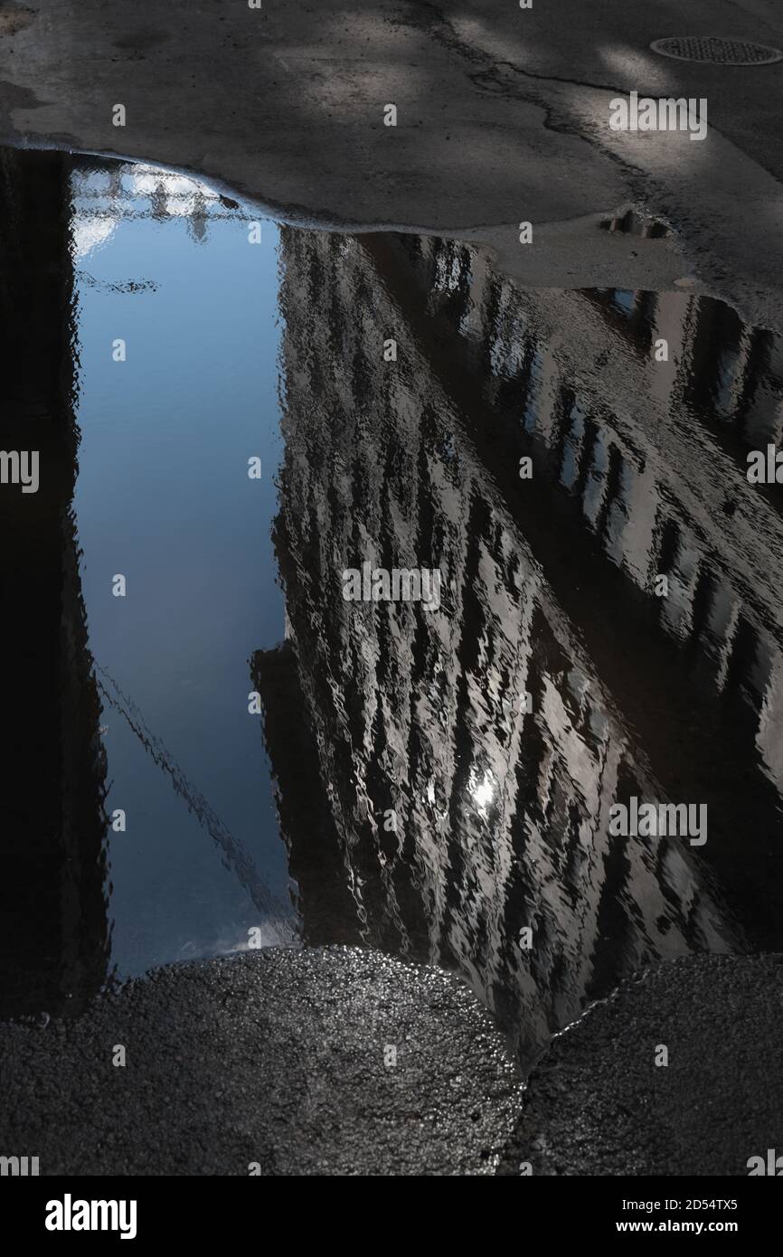 Riflessione gigante in puddle lungo Plymouth Street a DUMBO, Brooklyn, verso i ponti di Manhattan e Brooklyn. Strada deserta. Monocromatico, a toni. WA Foto Stock