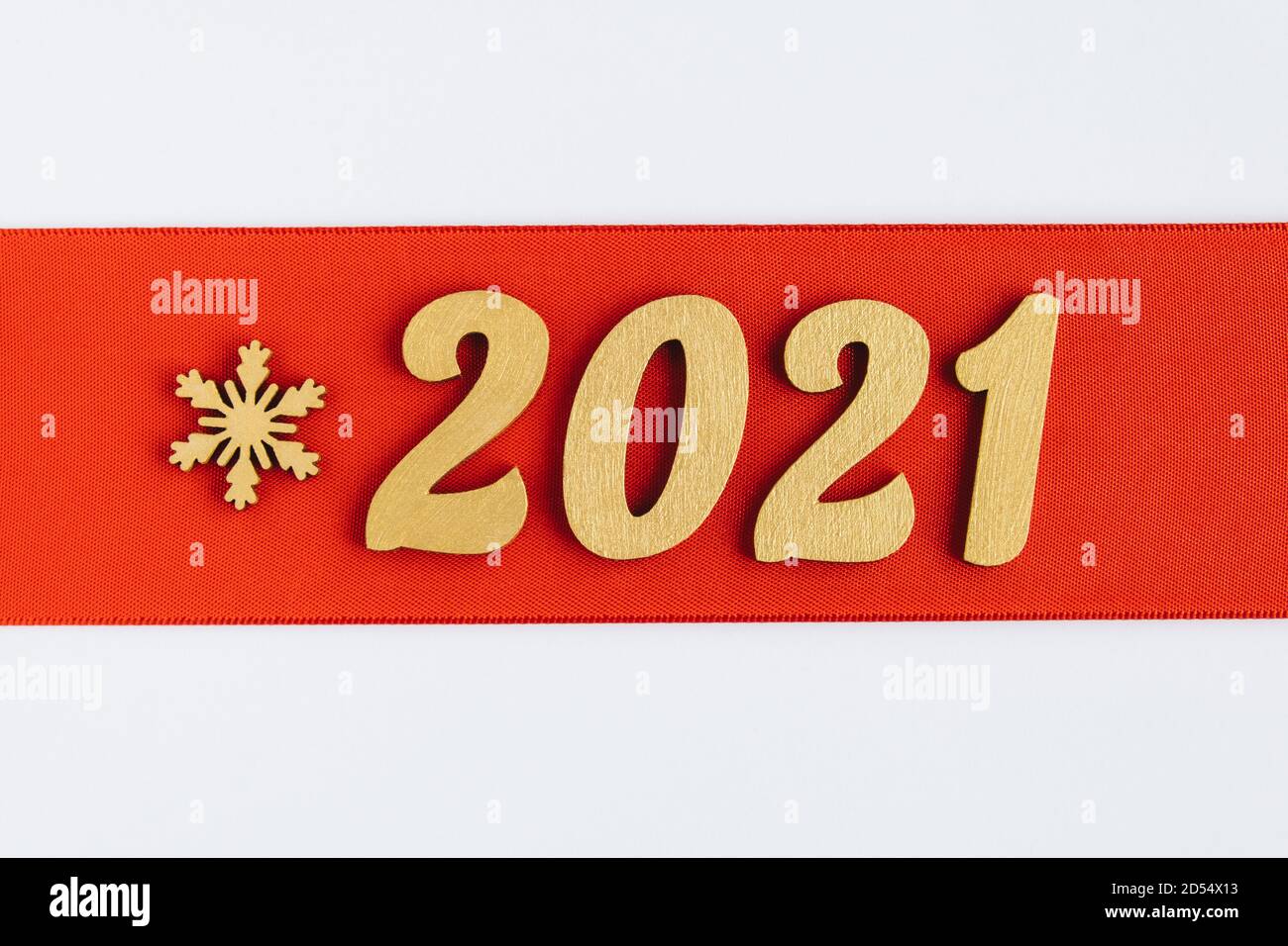 Sfondo festivo. Nastro rosso con il cartello dorato del 2021 e fiocco di neve. Banner festivo invernale. Buon Natale e Felice Anno Nuovo. Foto Stock
