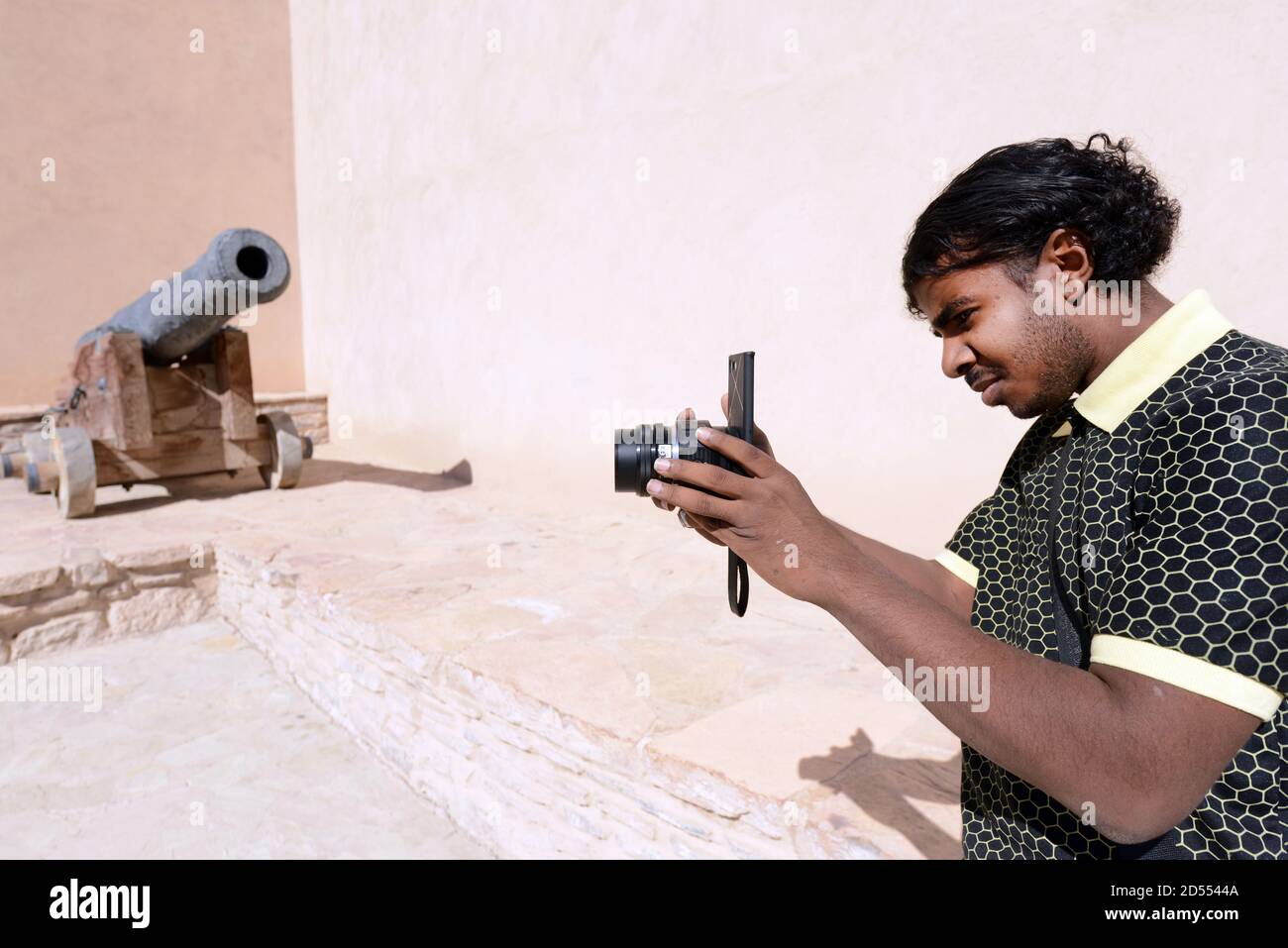 Un uomo che utilizza la fotocamera dello smartphone con un obiettivo esterno collegato. Foto Stock