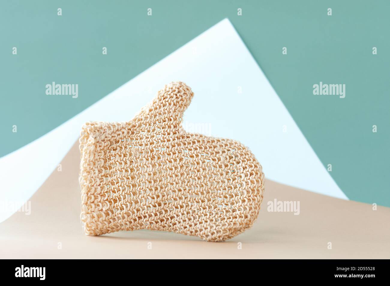 guanto beige ruvido per massaggio anticellulite e cura della pelle del corpo su colore bianco-nero geometrico, fuoco selettivo Foto Stock