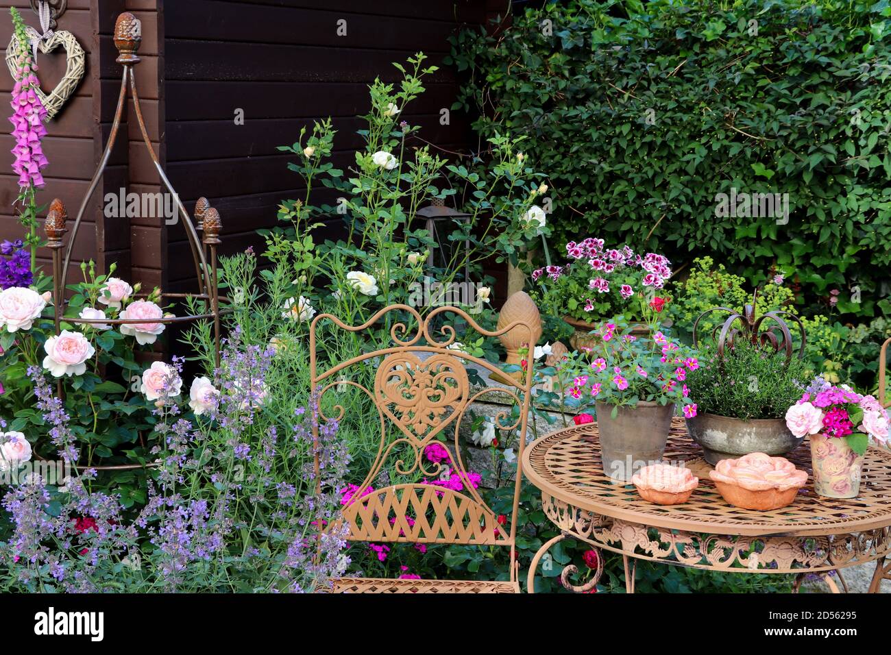 giardino estivo con rose inglesi, capannoni, thimble e mobili da giardino in ferro Foto Stock