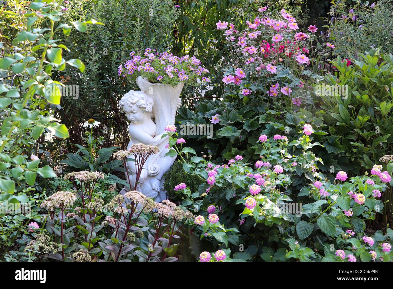 giardino estivo con putto e fiori rosa Foto Stock