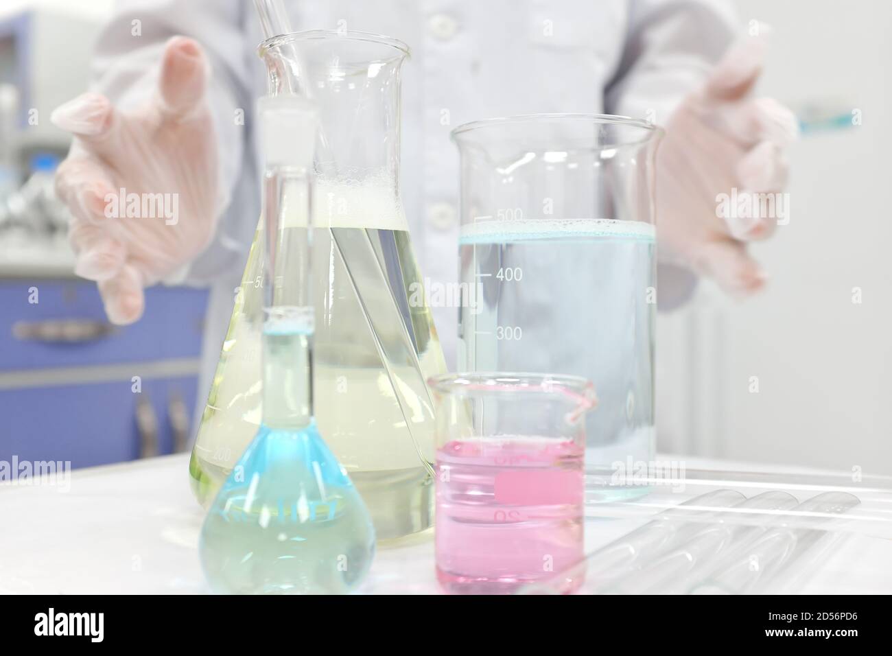 Fuoco selettivo di sostanze chimiche liquide colorate in becher di vetro, matraccio e tubo con le mani dello scienziato che lavorano. Background dell'esperimento della classe Chemistry Laboratory. Foto Stock