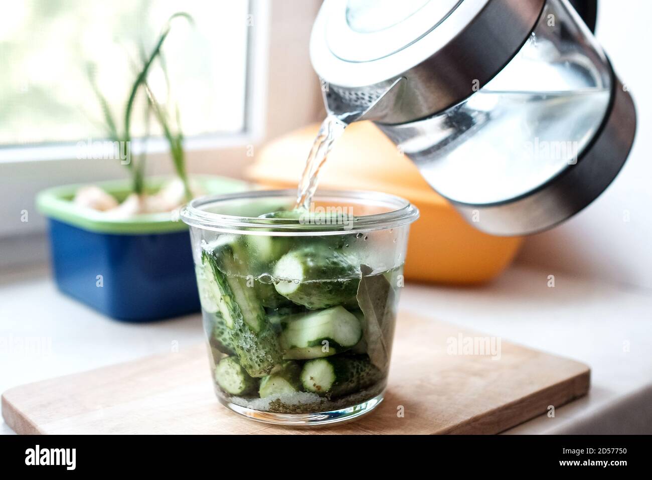 Cetrioli decapanti. Versare l'acqua bollente in un recipiente di vetro. Foto Stock