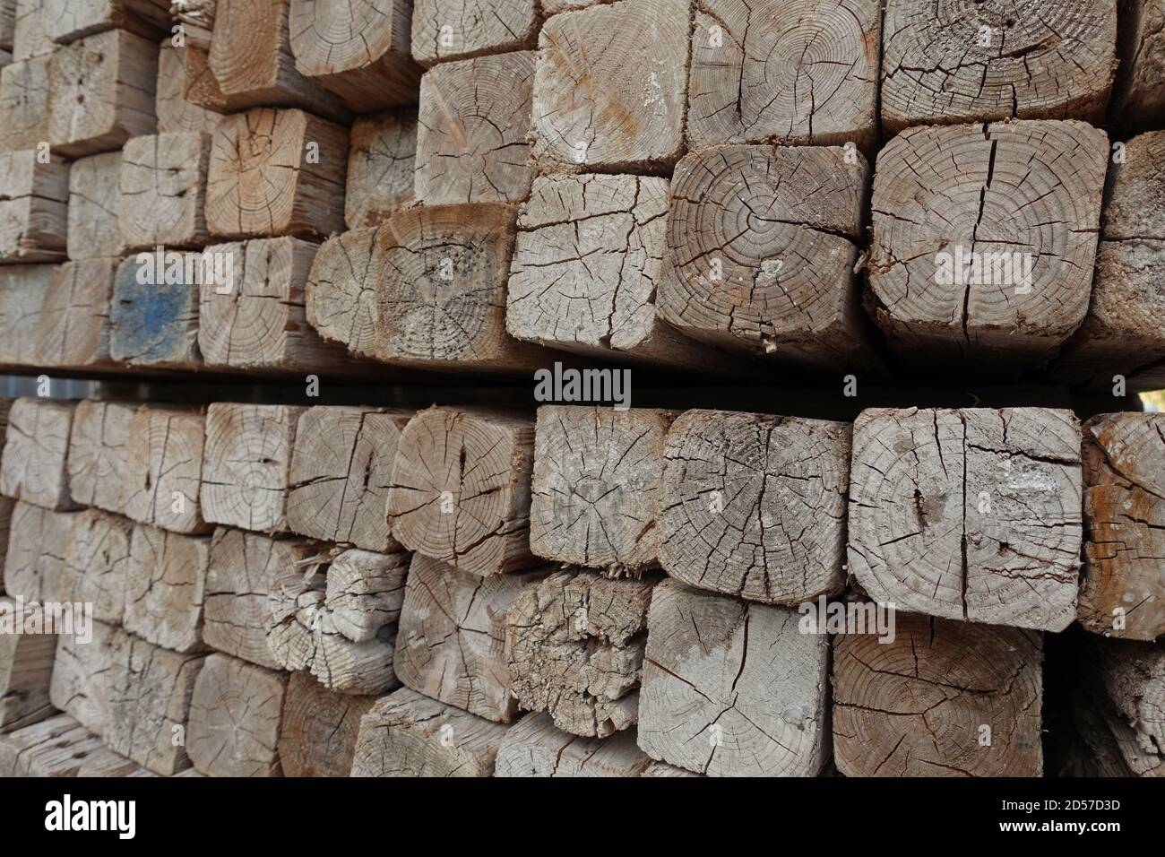 Pila di pali di legno quadrati in cantiere. Legno accatastato. Foto Stock