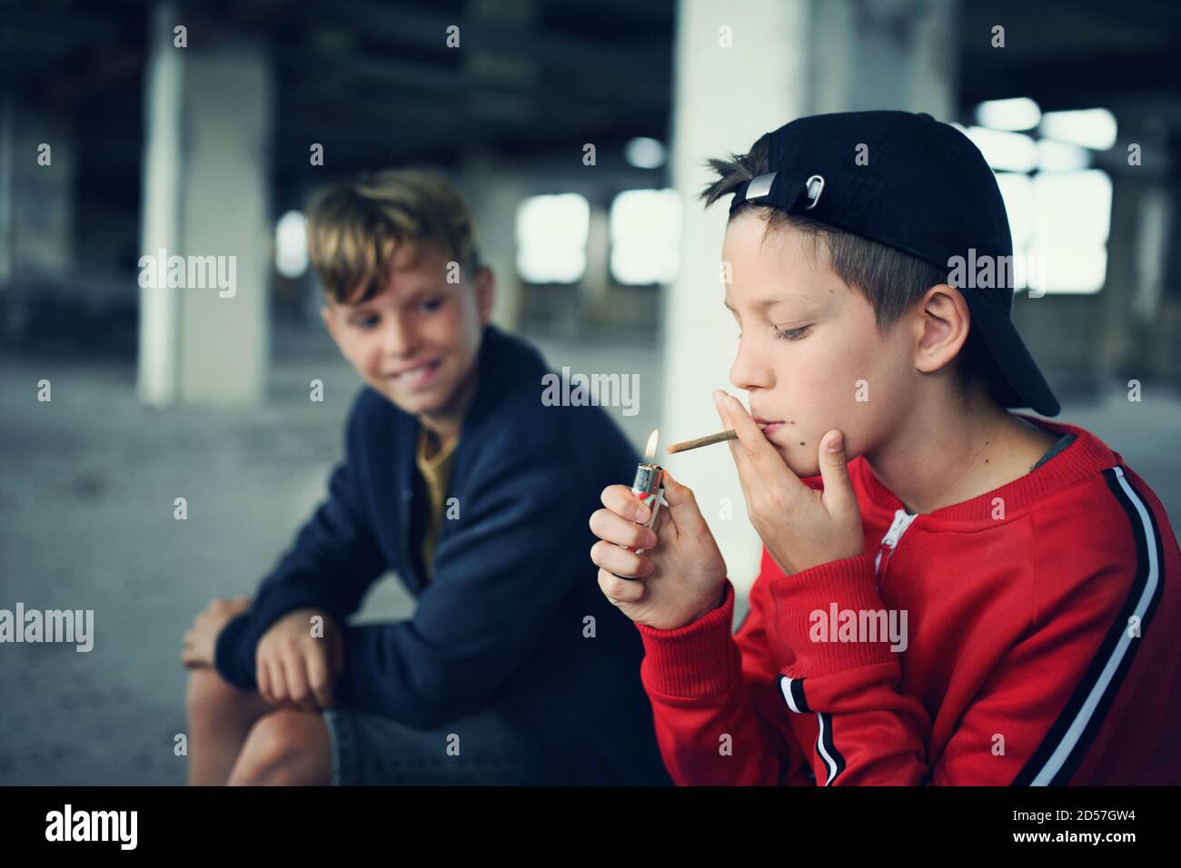 Gruppo di ragazzi adolescenti all'interno di un edificio abbandonato, sigarette fumanti. Foto Stock