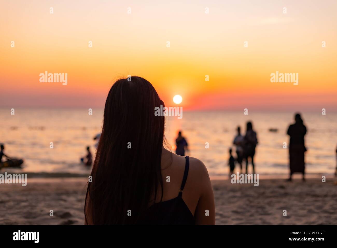 Silhouette al tramonto. Femmina sulla spiaggia contro il cielo passa fascio solare Foto Stock