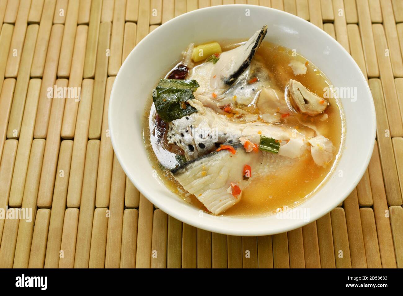 Testa di pesce di salmone piccante e funghi di paglia in Tom Yum zuppa sul recipiente Foto Stock