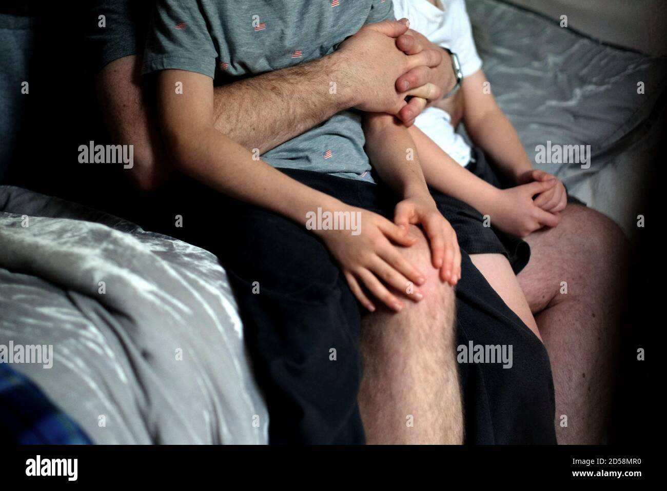 Due ragazzi seduti sul grembo del padre al momento di coricarsi Foto Stock